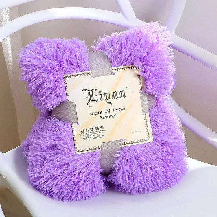 Purple super soft coral fleece blanket folded and secured with gray straps on white chair