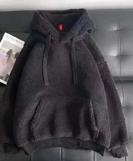 Black lamb wool sweatshirt with hood and front pocket displayed on black leather surface