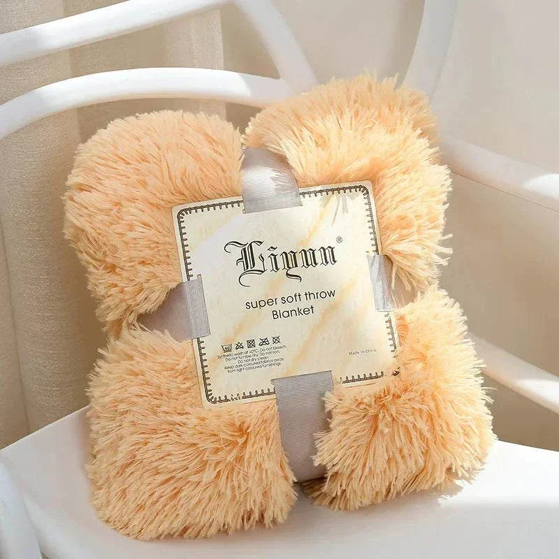 Soft fluffy coral fleece blanket in light peach color folded with label on white chair