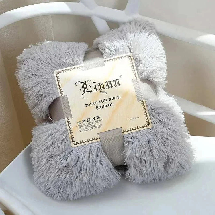 Fluffy gray coral fleece blanket folded with packaging label on white chair