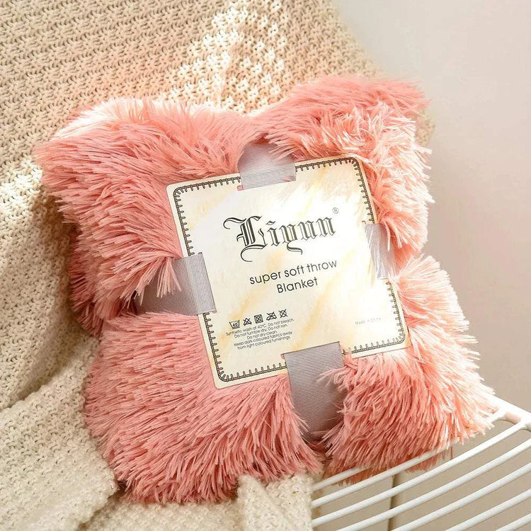 pink super soft coral fleece blanket with fluffy texture on beige knitted fabric background