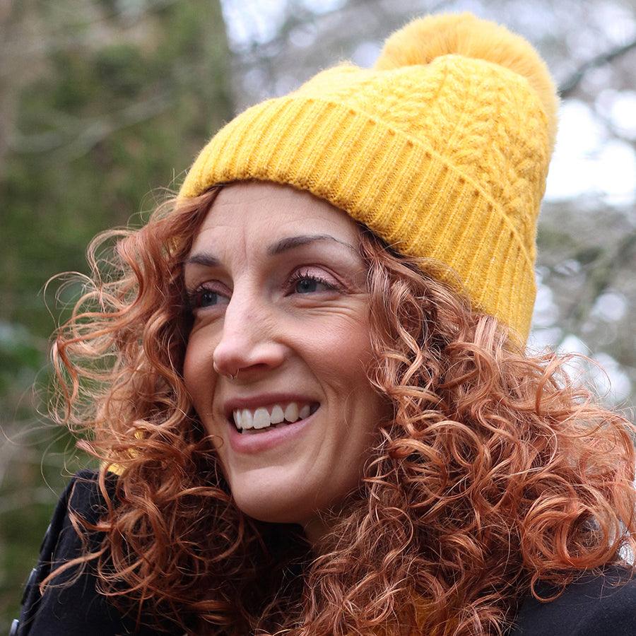 woman wearing yellow recycled yarn herringbone cable knit hat outdoors