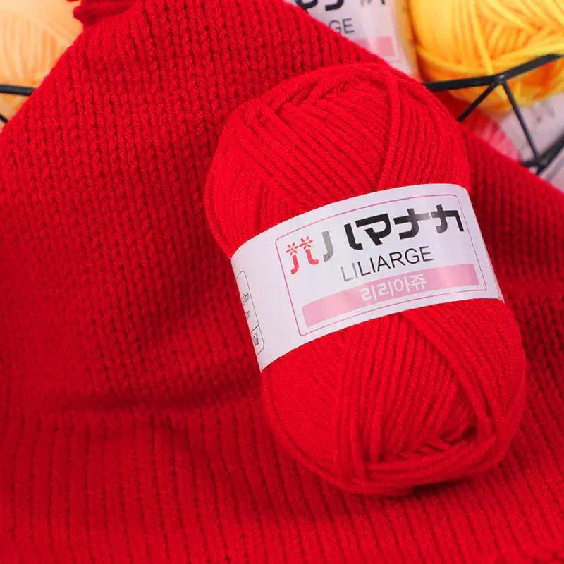 Red 4-ply Milk Cotton Yarn ball on matching knitted fabric for baby dolls and crochet projects