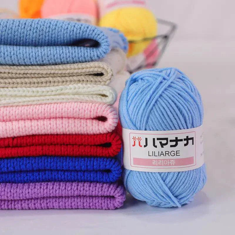 Soft blue 4-ply milk cotton yarn ball next to neatly folded colorful knitted fabric pieces