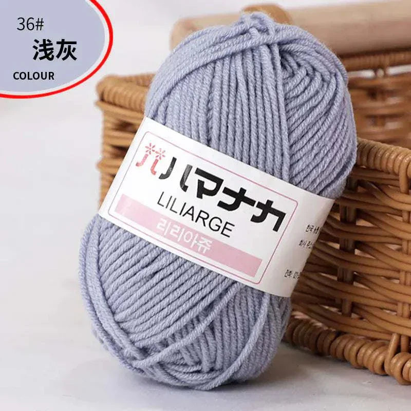 Light gray 4-ply Milk Cotton Yarn ball for baby dolls and crochet projects next to wicker basket