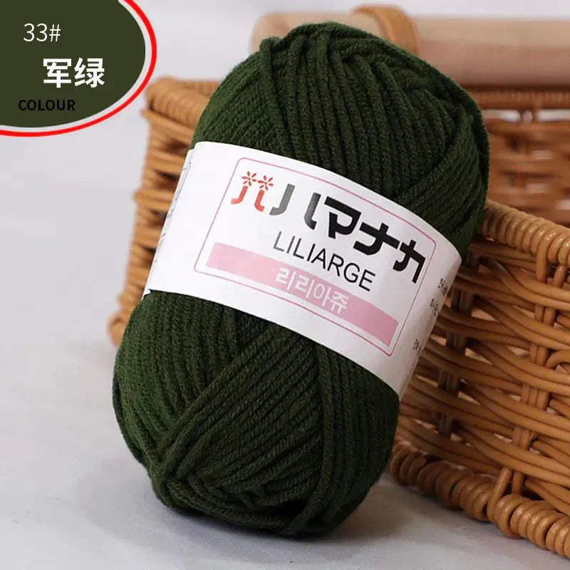 Dark green 4-ply milk cotton yarn ball for baby dolls and crochet placed near wicker basket