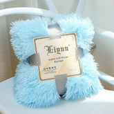 Light blue super soft coral fleece blanket folded on white chair with packaging label