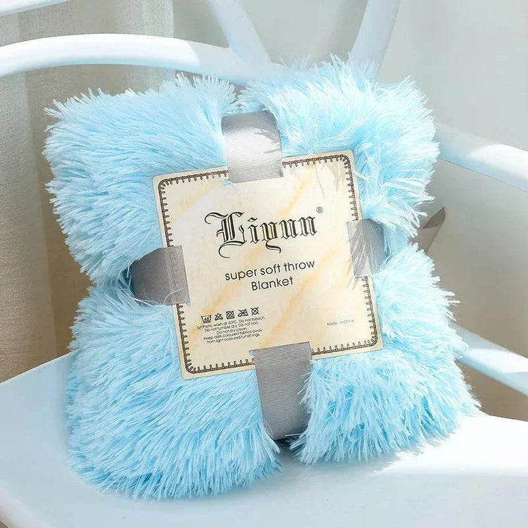 Light blue super soft coral fleece blanket folded on white chair with packaging label