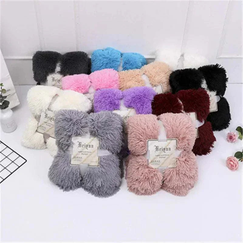 Collection of super soft coral fleece blankets in various colors displayed on a white surface for cozy bedding and sofa use