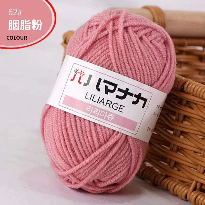 Soft pink 4-ply milk cotton yarn ball for baby dolls and crochet projects with label and wicker basket background