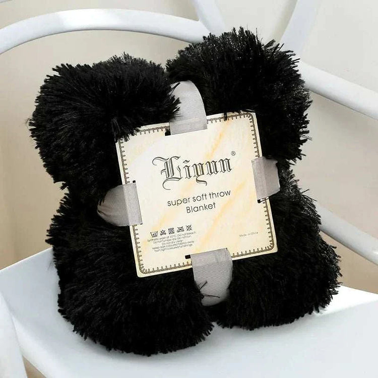 Black super soft coral fleece blanket folded with label on white chair